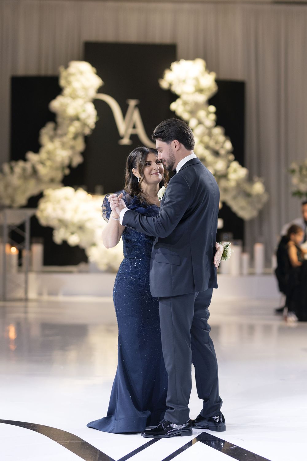 Romantic couple sharing intimate dance moments on an elegant white dance floor with illuminated floral decor.