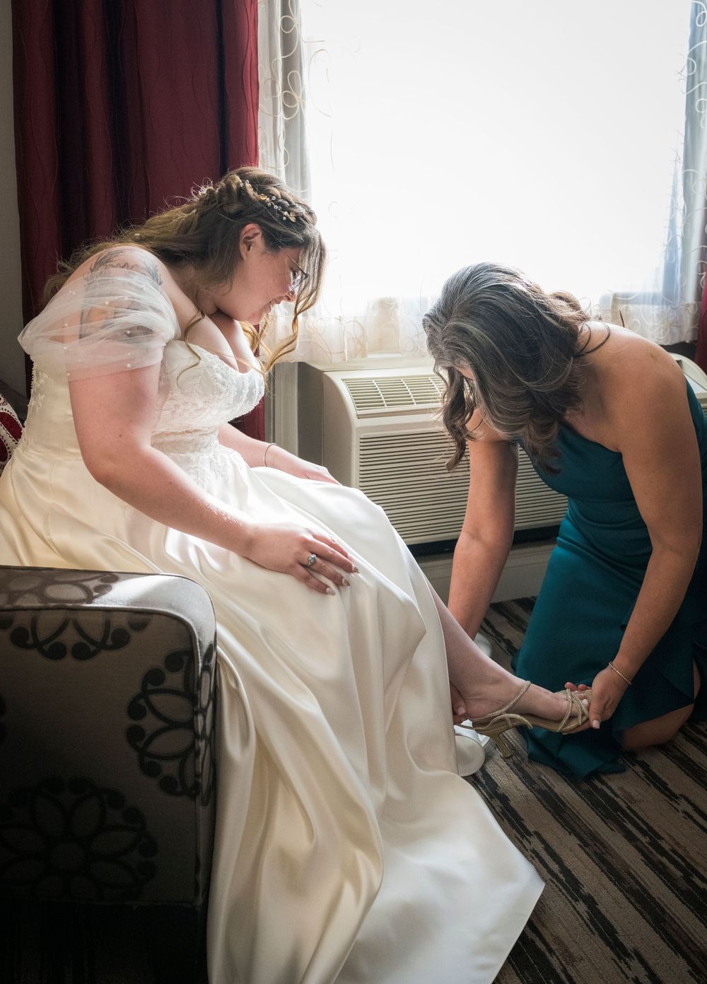 Wedding dress being adjusted and fitted in a sunlit room with soft window lighting.