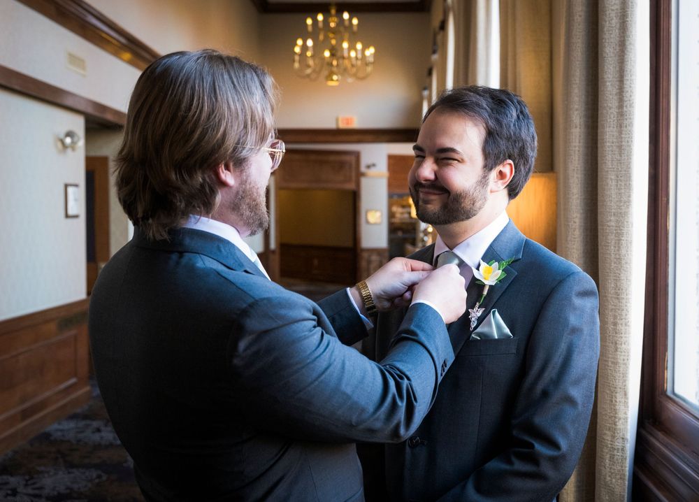 A sequence of intimate moments between wedding attendees in an elegant indoor venue with chandelier lighting.