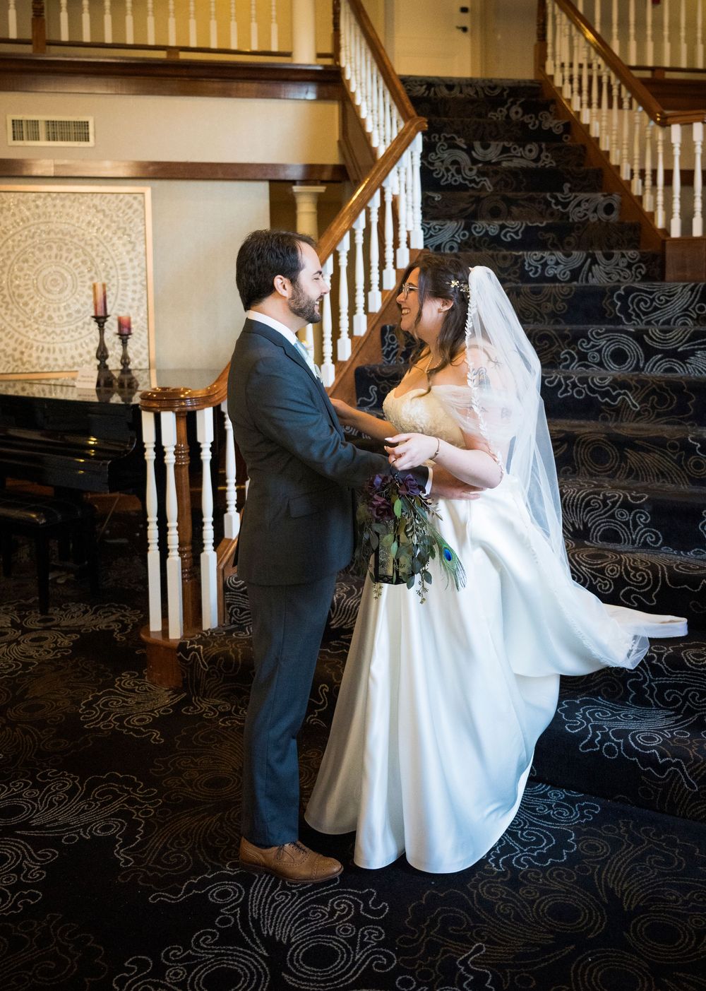 Couple dancing on a staircase with elegant white banister during their wedding celebration.