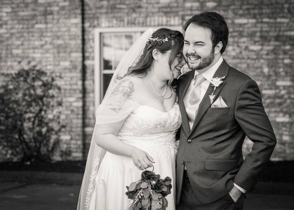 Black and white outdoor wedding portraits against a rustic brick wall backdrop.