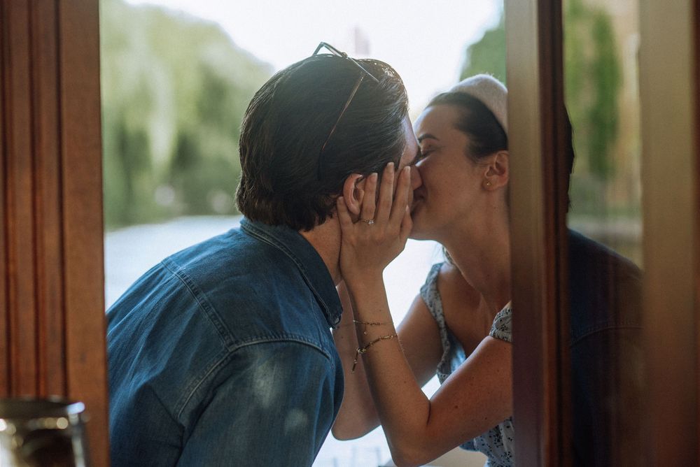 Intimate moments shared inside vintage boat cabin with sunlight filtering through windows.