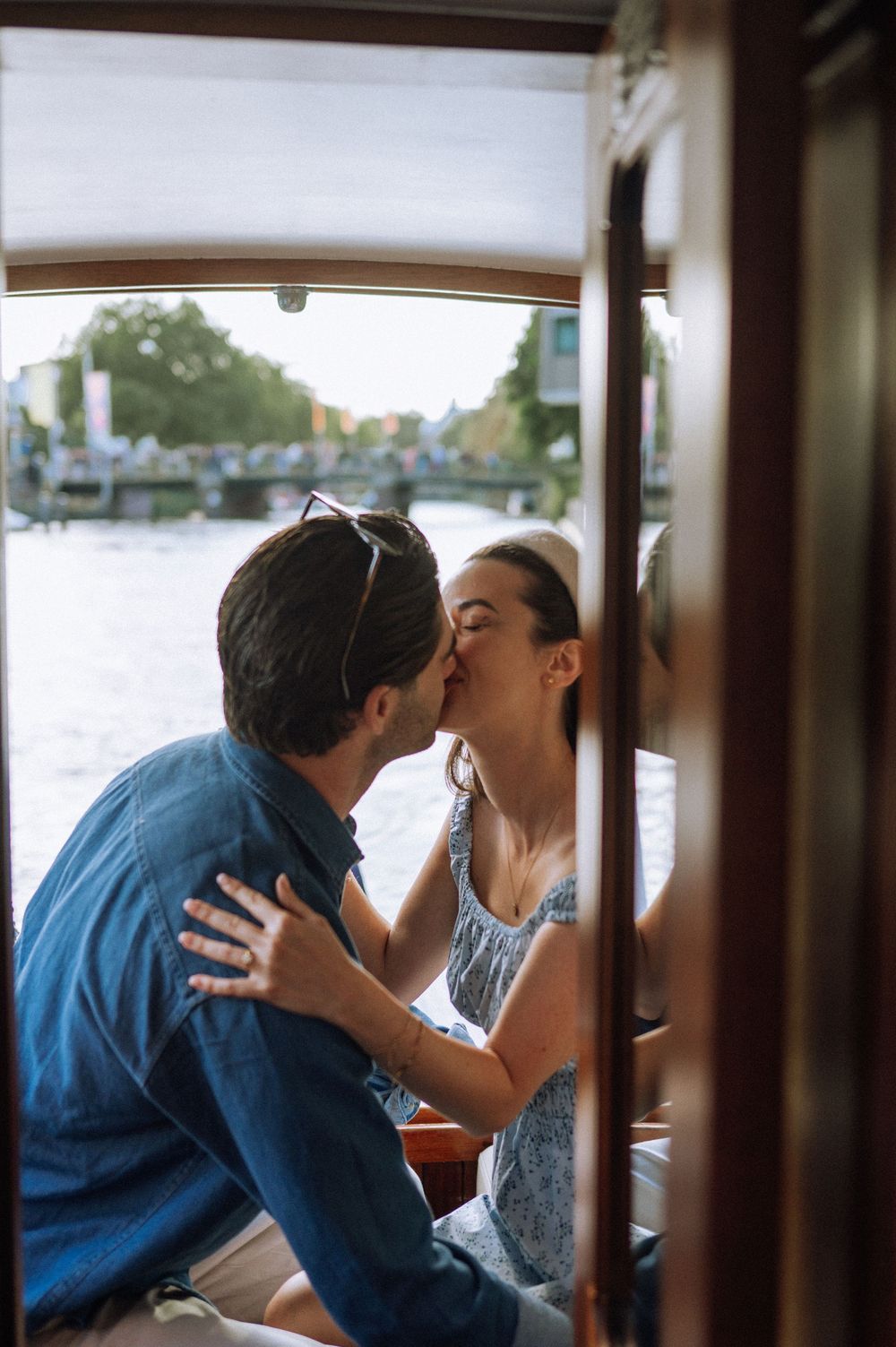 Romantic moment captured inside wooden boat cabin with canal view through windows.