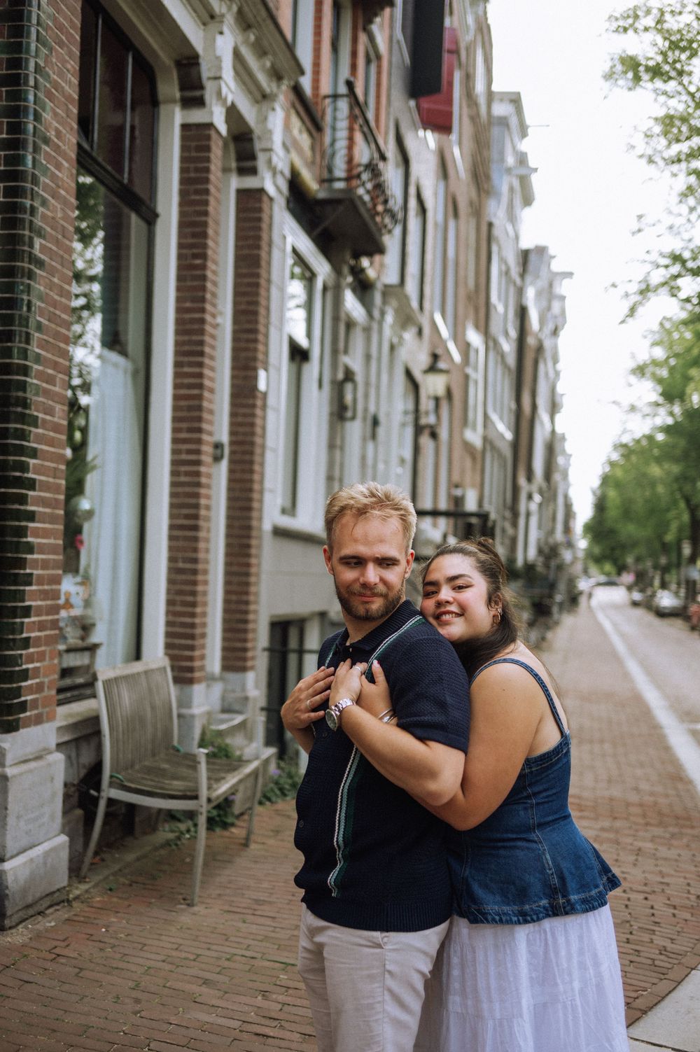A couple laughs together on a brick-paved street in Amsterdam.