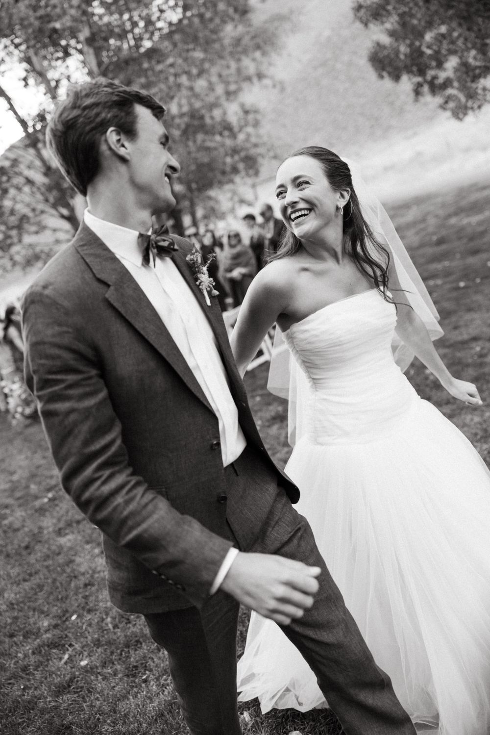 A romantic black and white wedding photography sequence showing joyful candid moments between newlyweds outdoors.