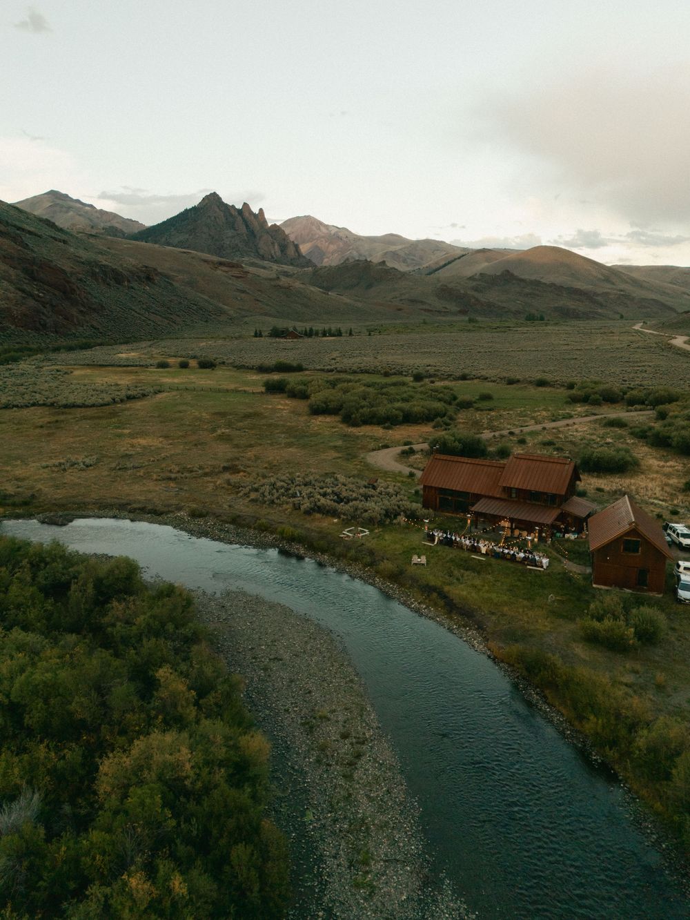 Scenic mountain landscape with a winding river and rustic cabins nestled in the valley.