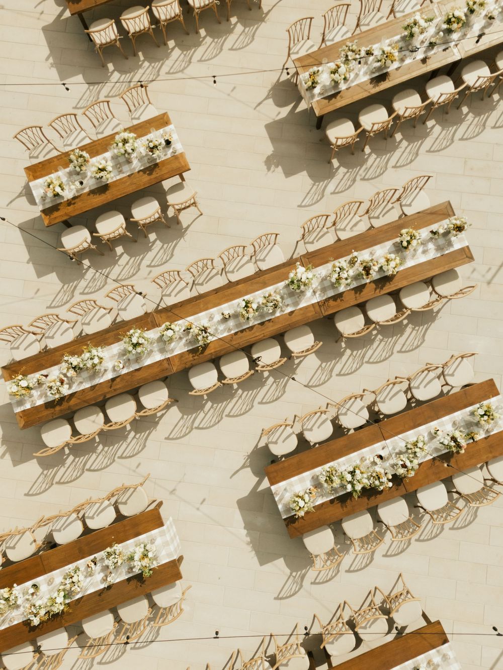 Overhead view of elegant wedding reception tables arranged in rows with white chairs and floral centerpieces.
