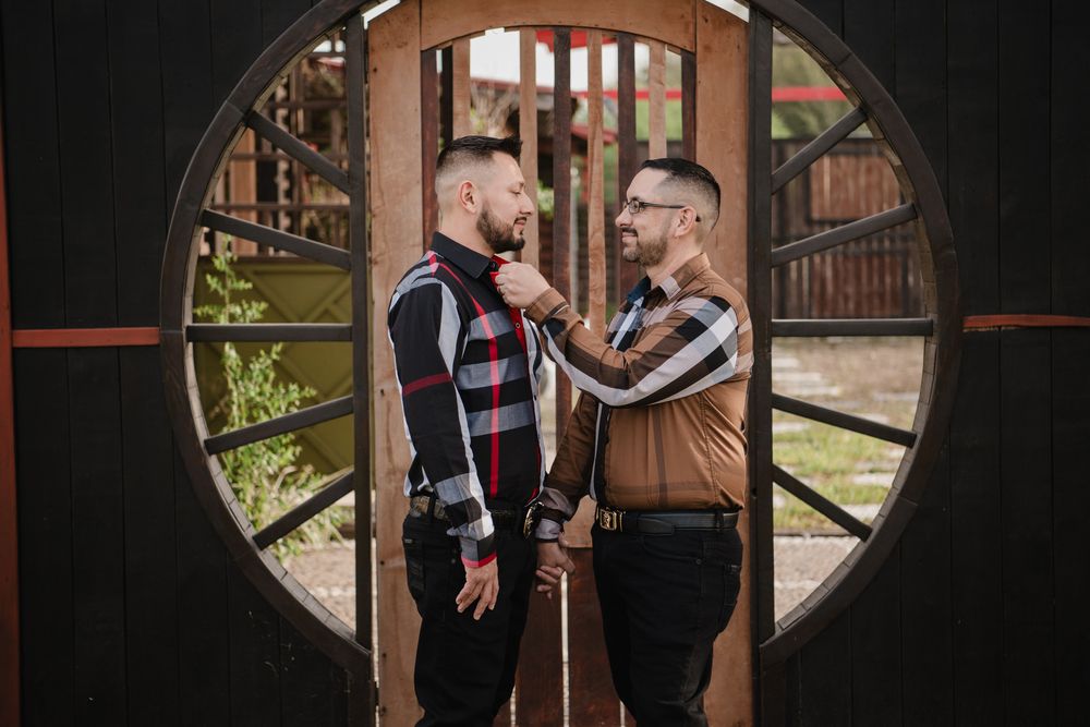 A couple embraces in front of a rustic wooden door during an engagement photo session.