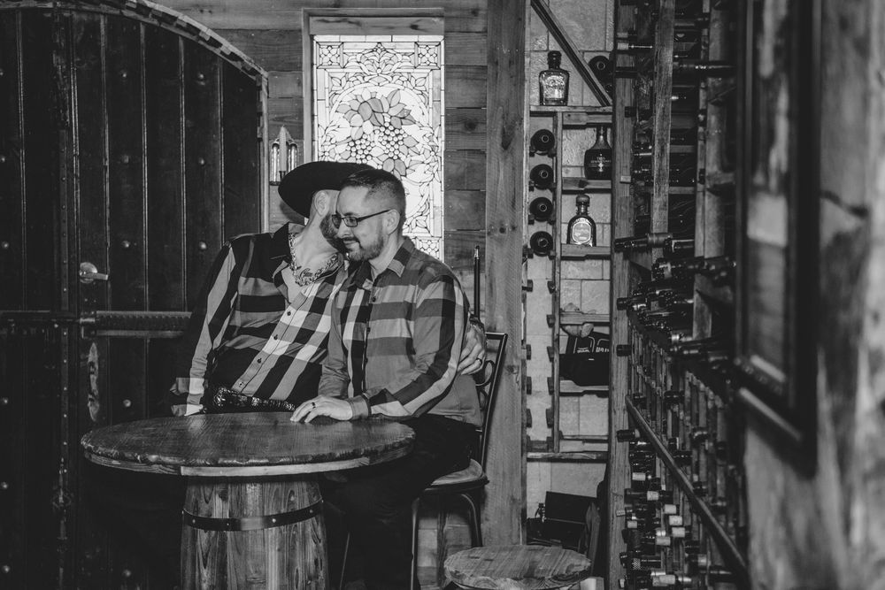 A person in plaid sits at a rustic wooden table in a dimly lit vintage industrial space.