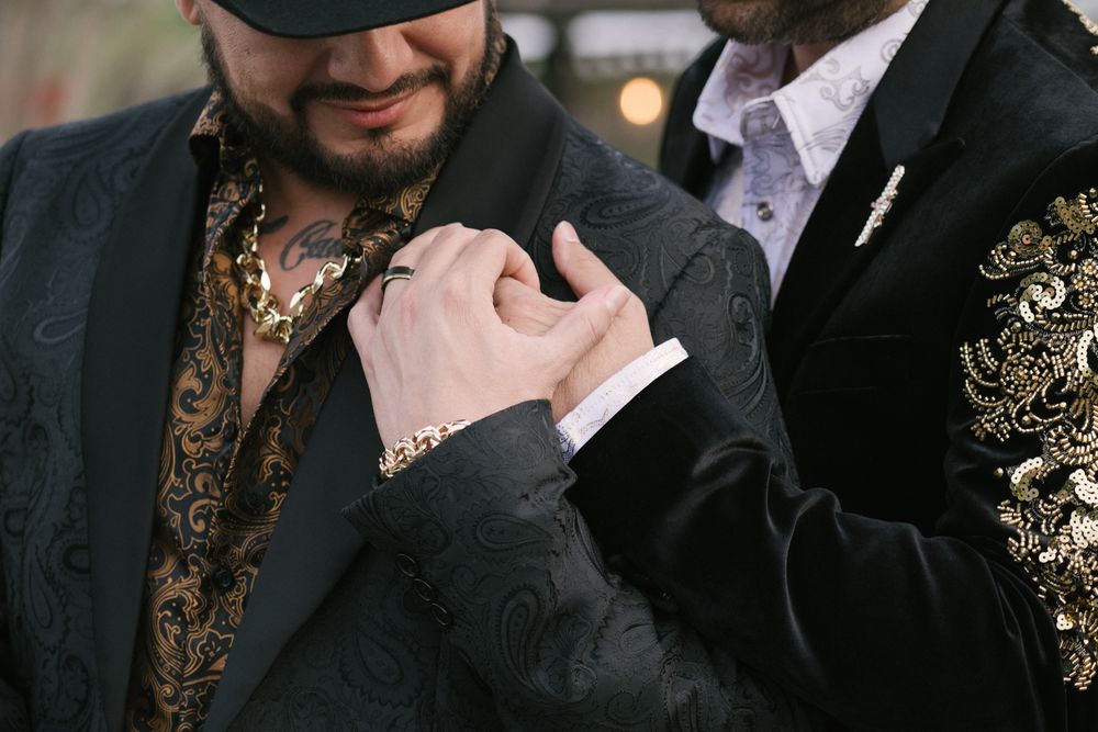 A close-up view shows hands and formal attire details in a dimly lit indoor setting.