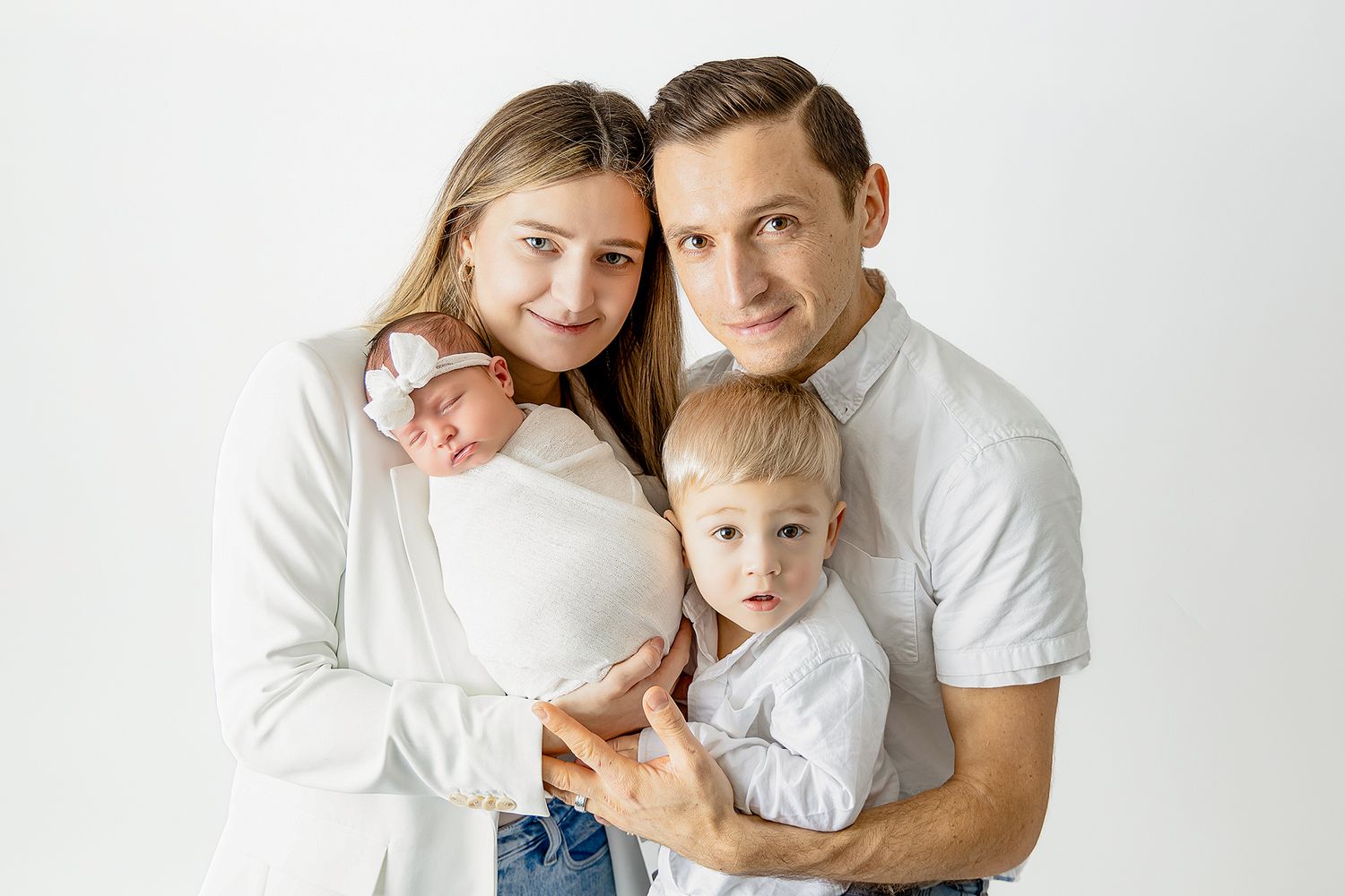 A family wearing white and denim outfits poses together for a series of casual portrait photographs.