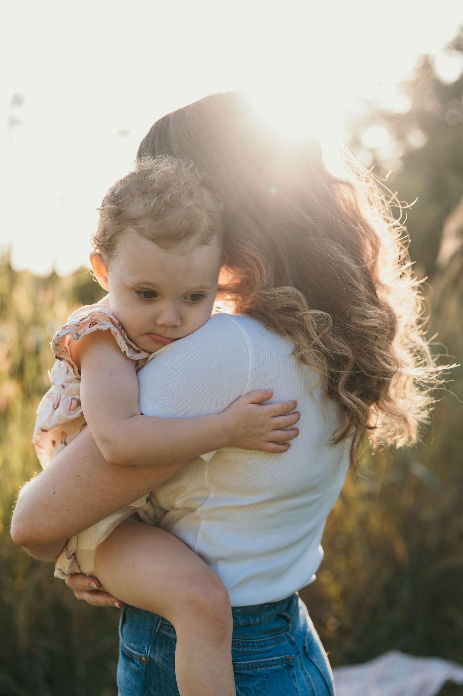 Mother and daughter hugging by lake during sunset in Walnut Creek recreational area in Nebraska.