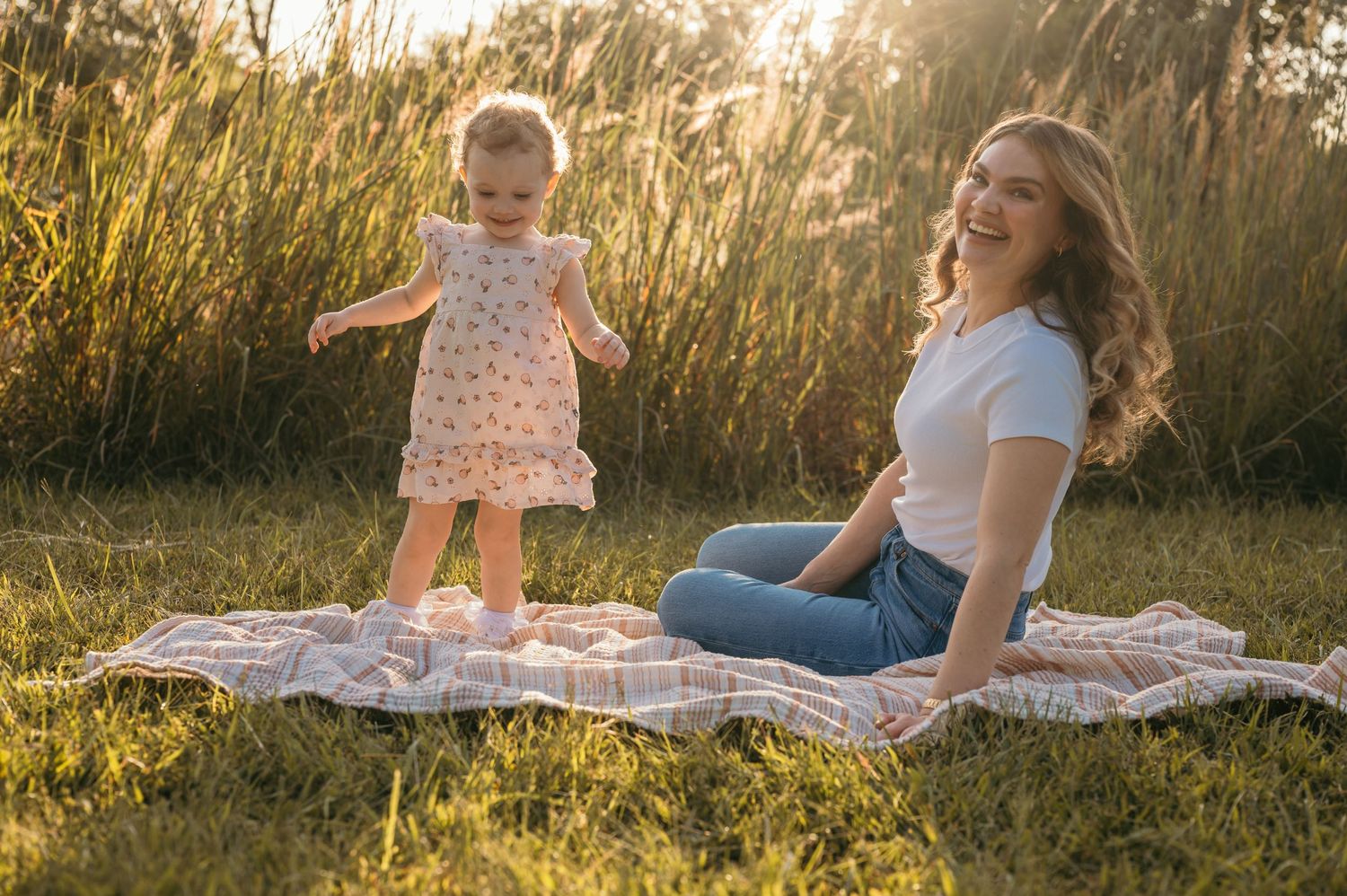 Mother and daughter playing by lake during sunset in Walnut Creek recreational area in Nebraska.