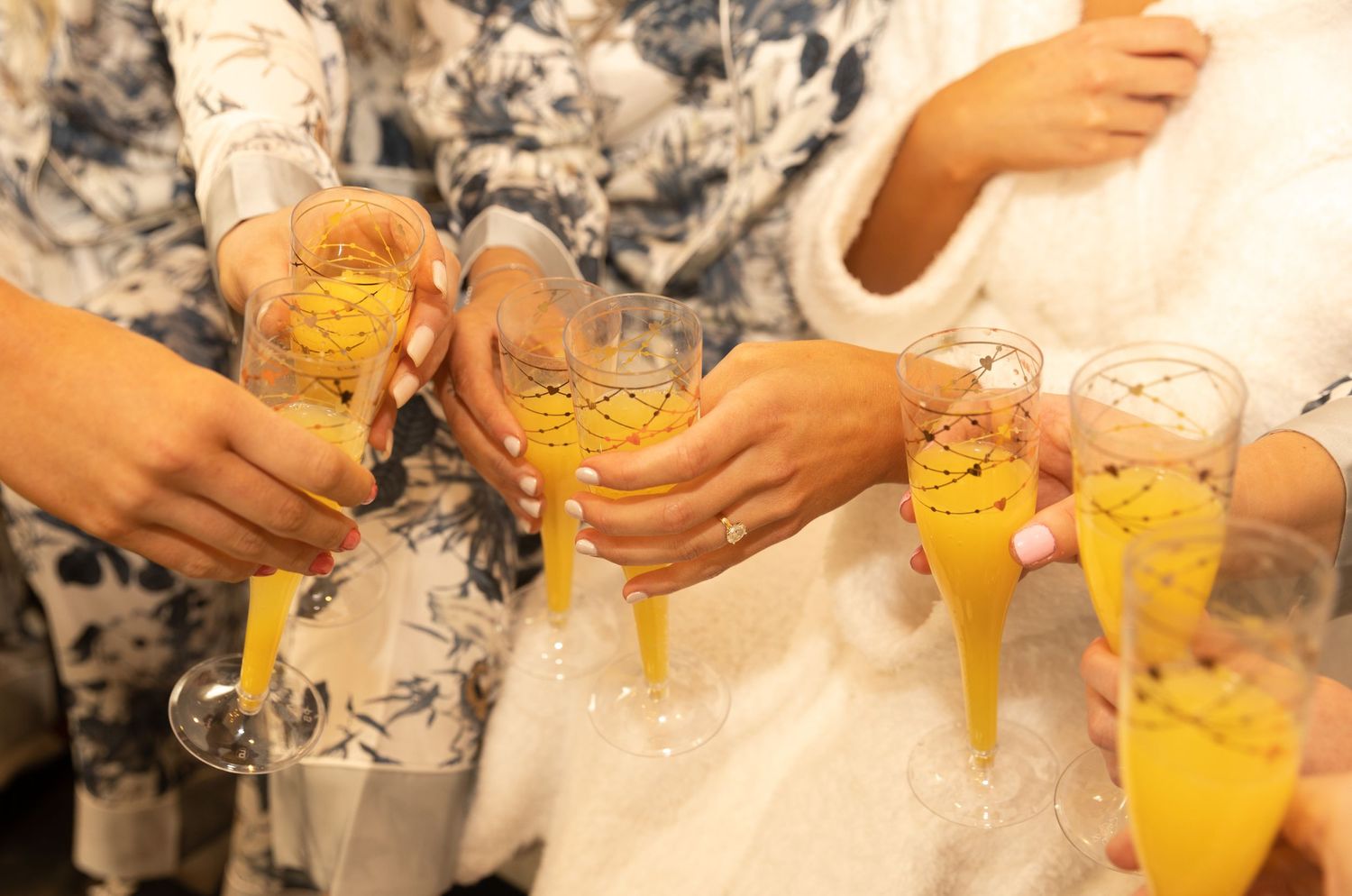 Wedding guests toast with orange mimosas in champagne flutes.