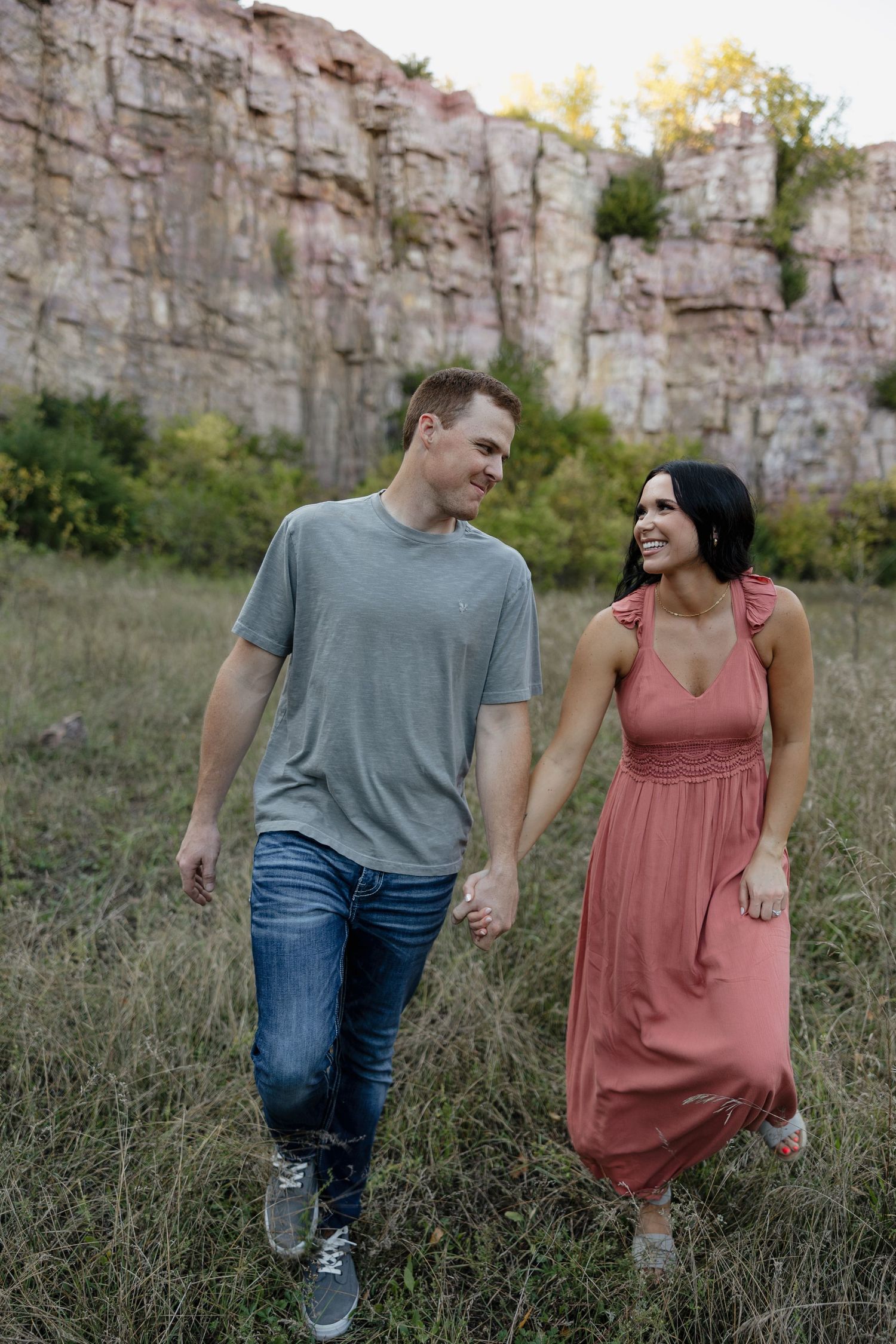 A couple takes a casual stroll together near a limestone quarry wall.