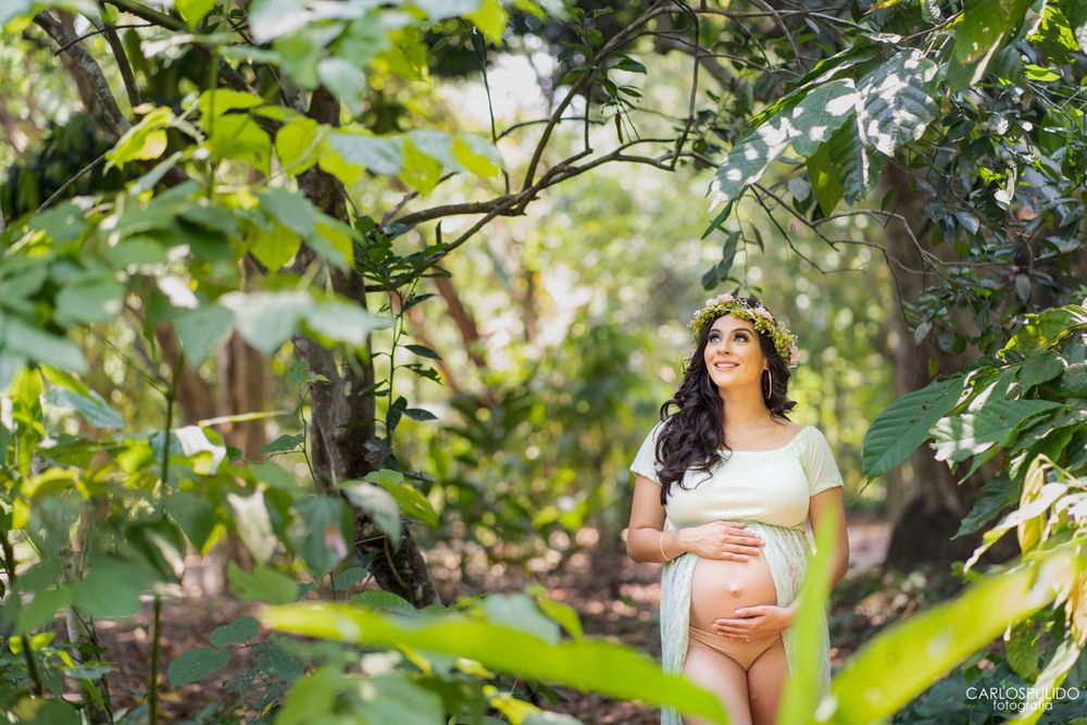 Artistic maternity portrait through tropical leaves in a garden setting.