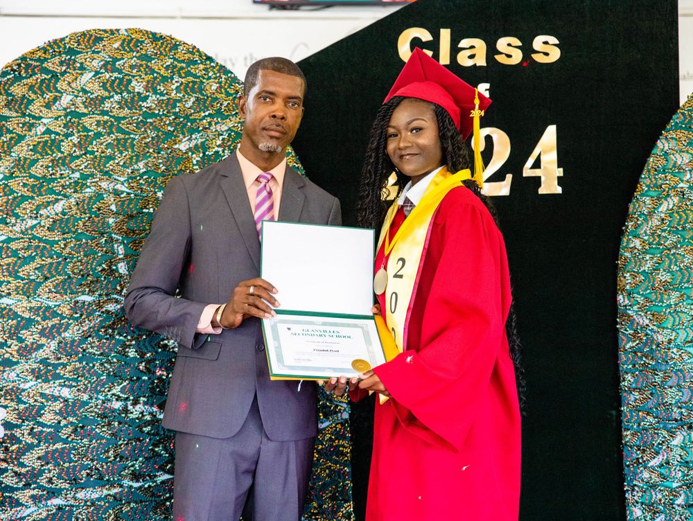 Graduate accepting diploma from presenter at Class of 2024 graduation ceremony.