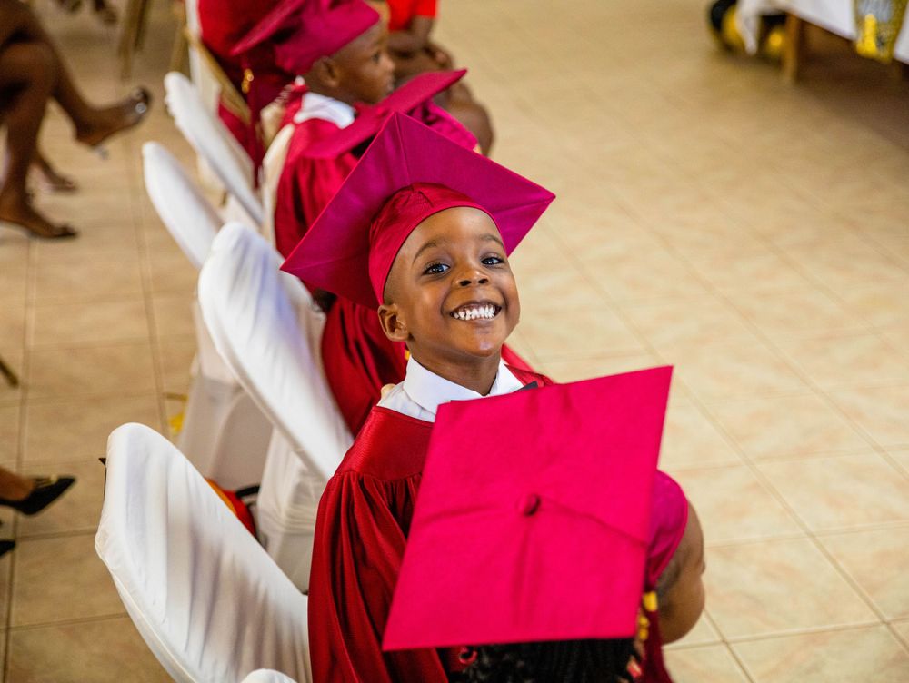 A graduate in a bright red cap and gown smiles joyfully during the celebration.