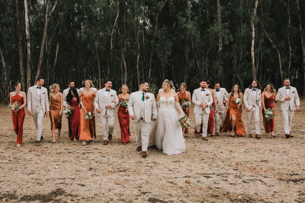 Wedding party in earth tones stands together against backdrop of eucalyptus forest.