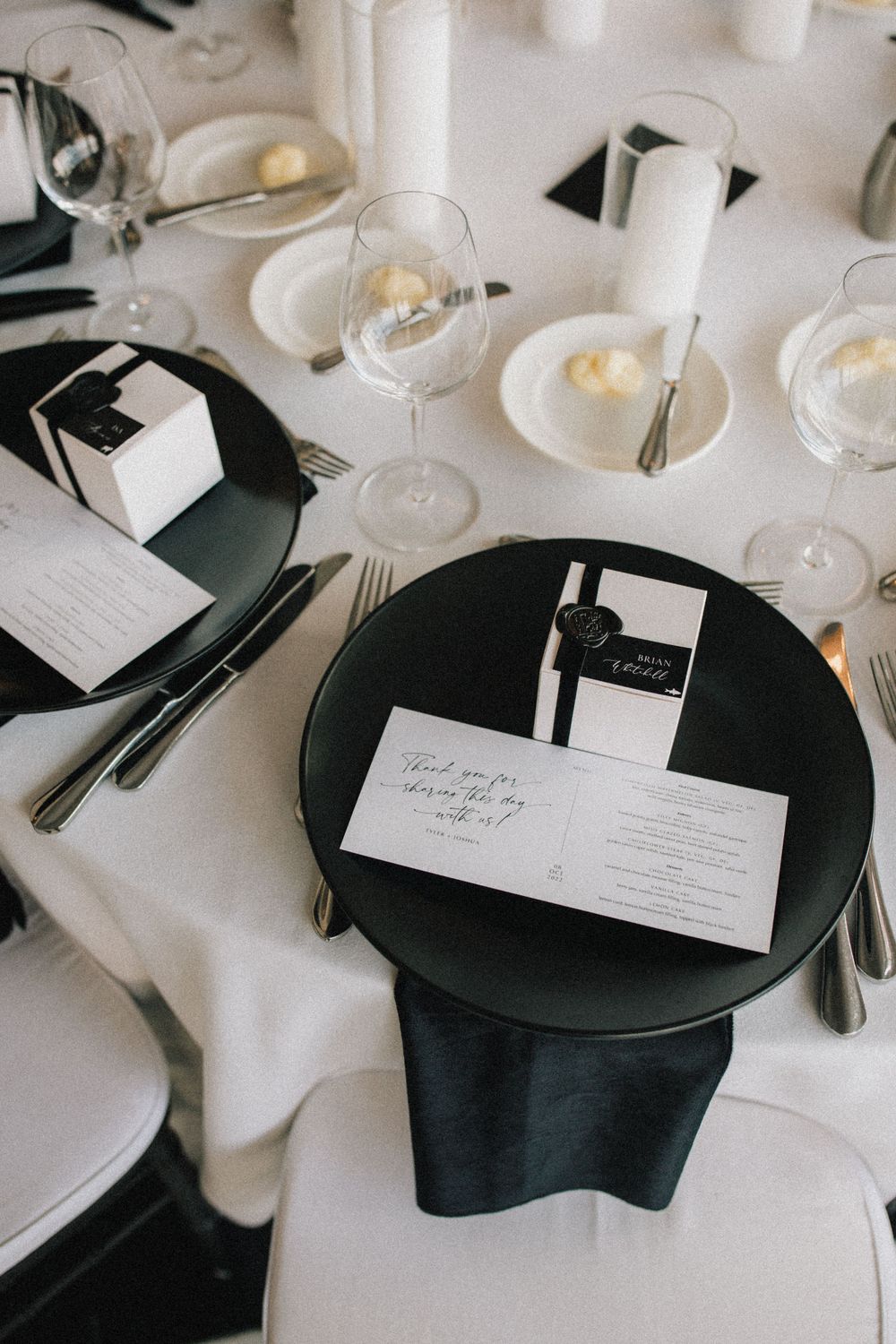 Elegant black and white place settings with wedding stationery and wine glasses on crisp linens.