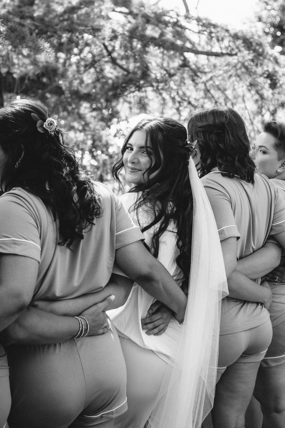 Bridesmaids in matching dusty rose dresses share a candid moment during wedding festivities.
