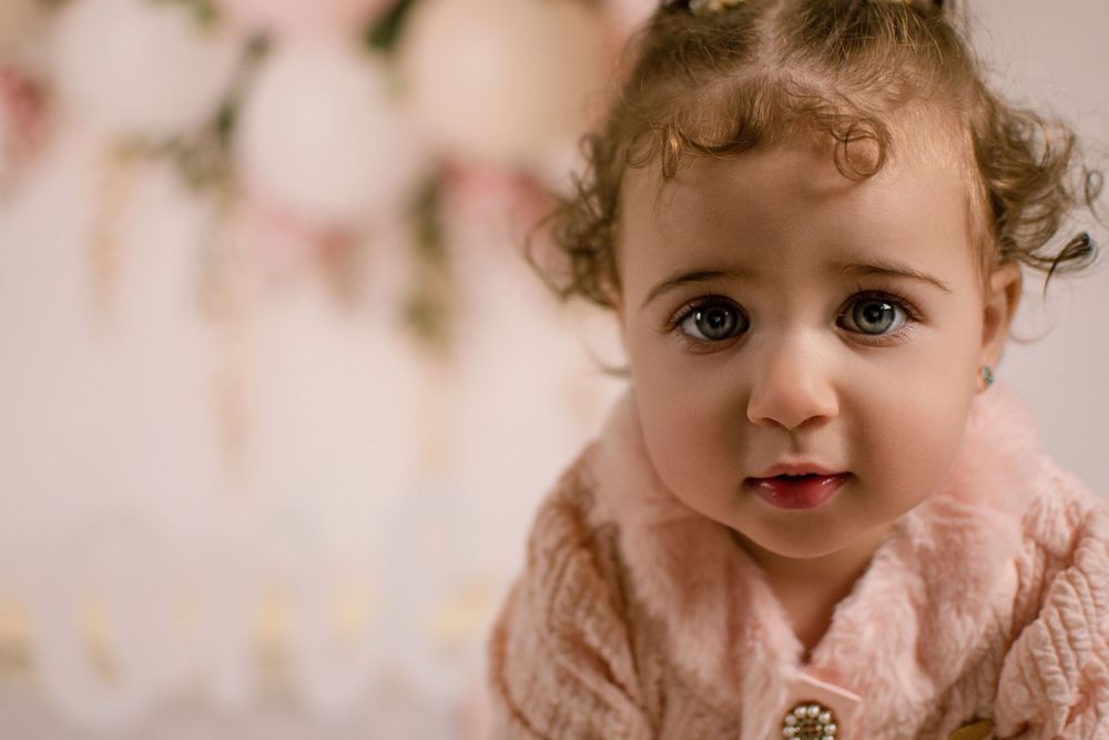 Close up portrait with pink floral and balloon decorations in soft lighting.