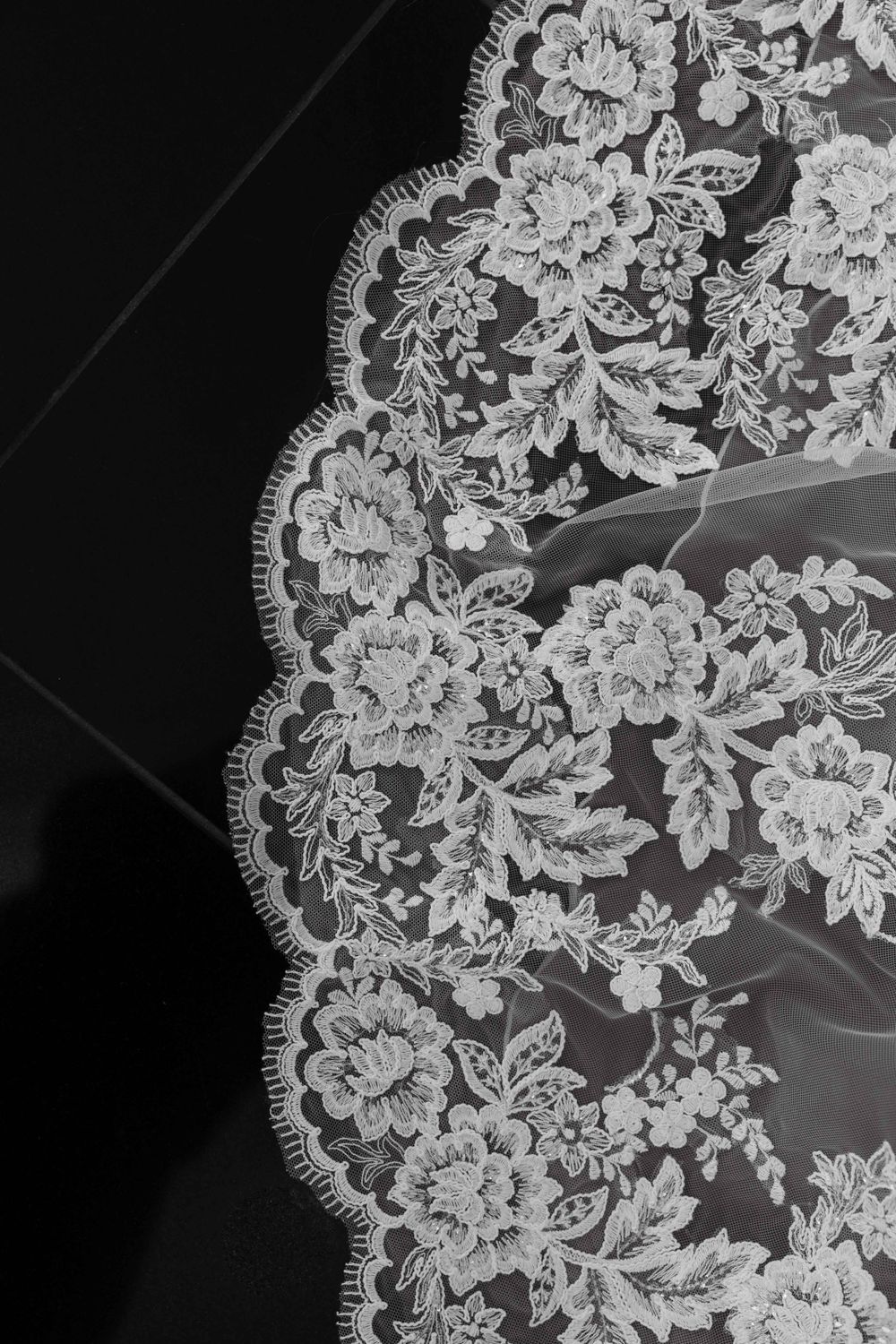 Intricate white lace detail with scalloped edges against a black background.