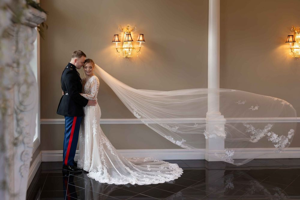 A romantic wedding portrait with flowing veil in an elegant room with wall sconces.