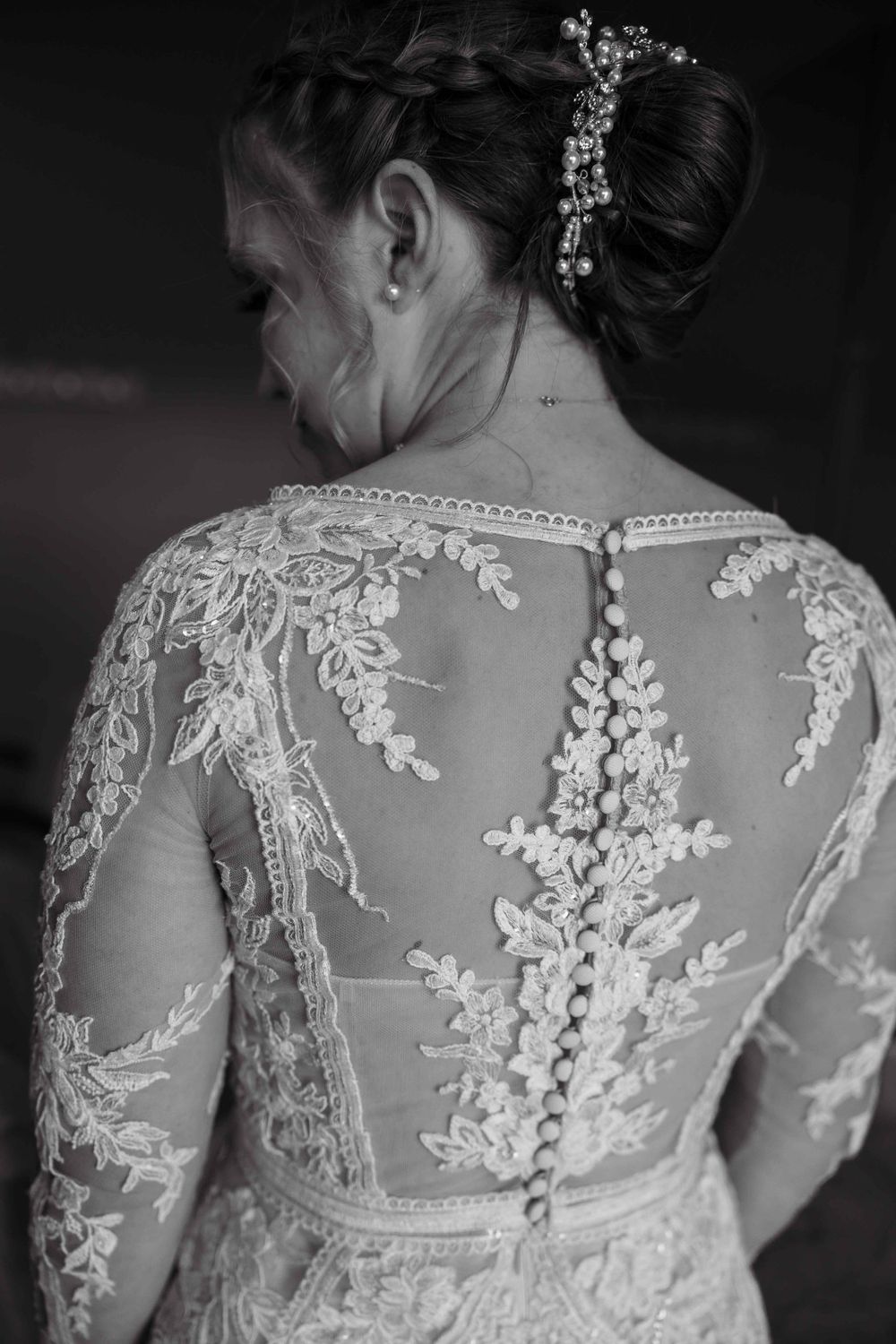 Delicate lace detailing on the back of a white wedding dress with sheer fabric and floral appliques.