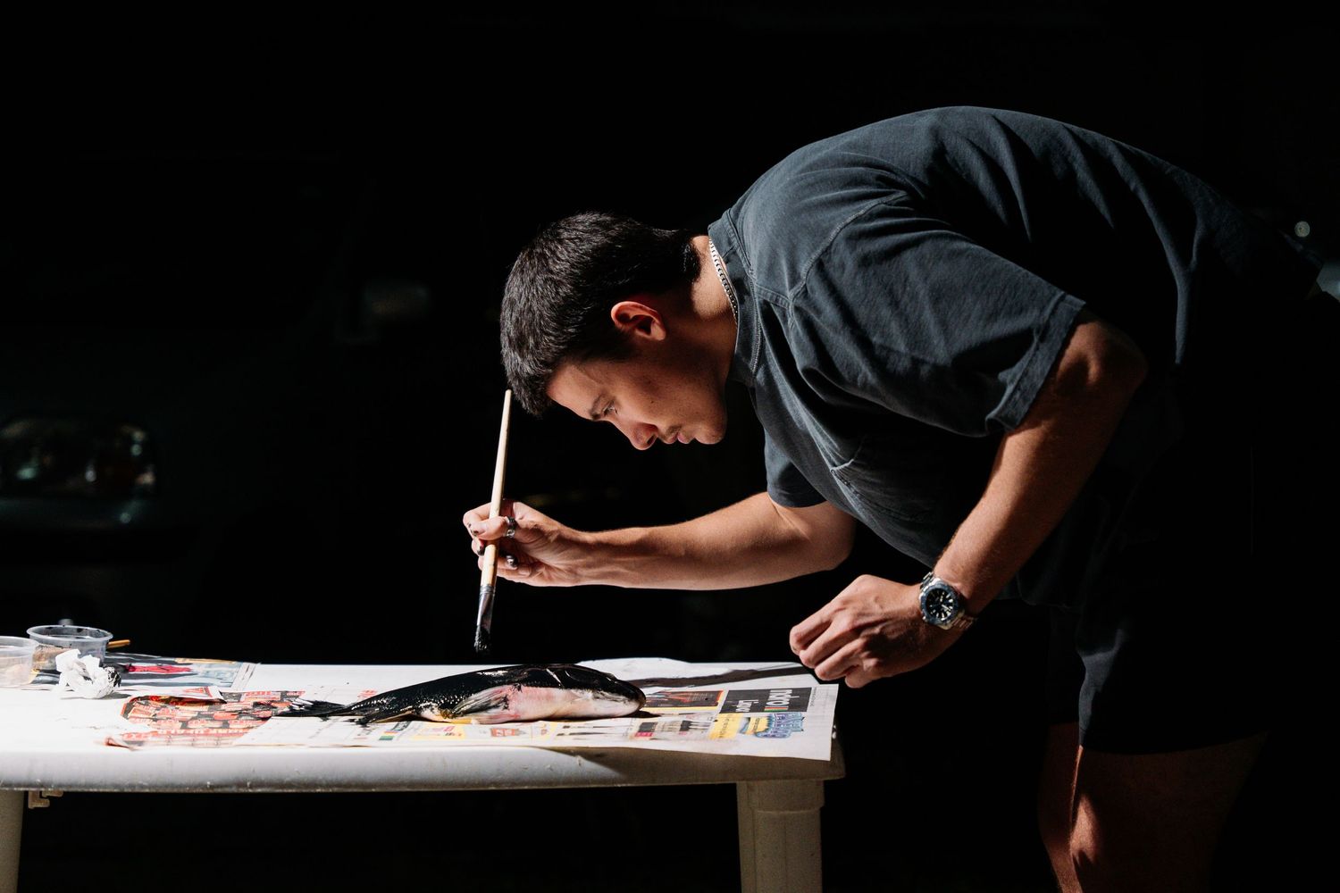 Overhead view of someone sketching detailed fish illustrations on white paper.