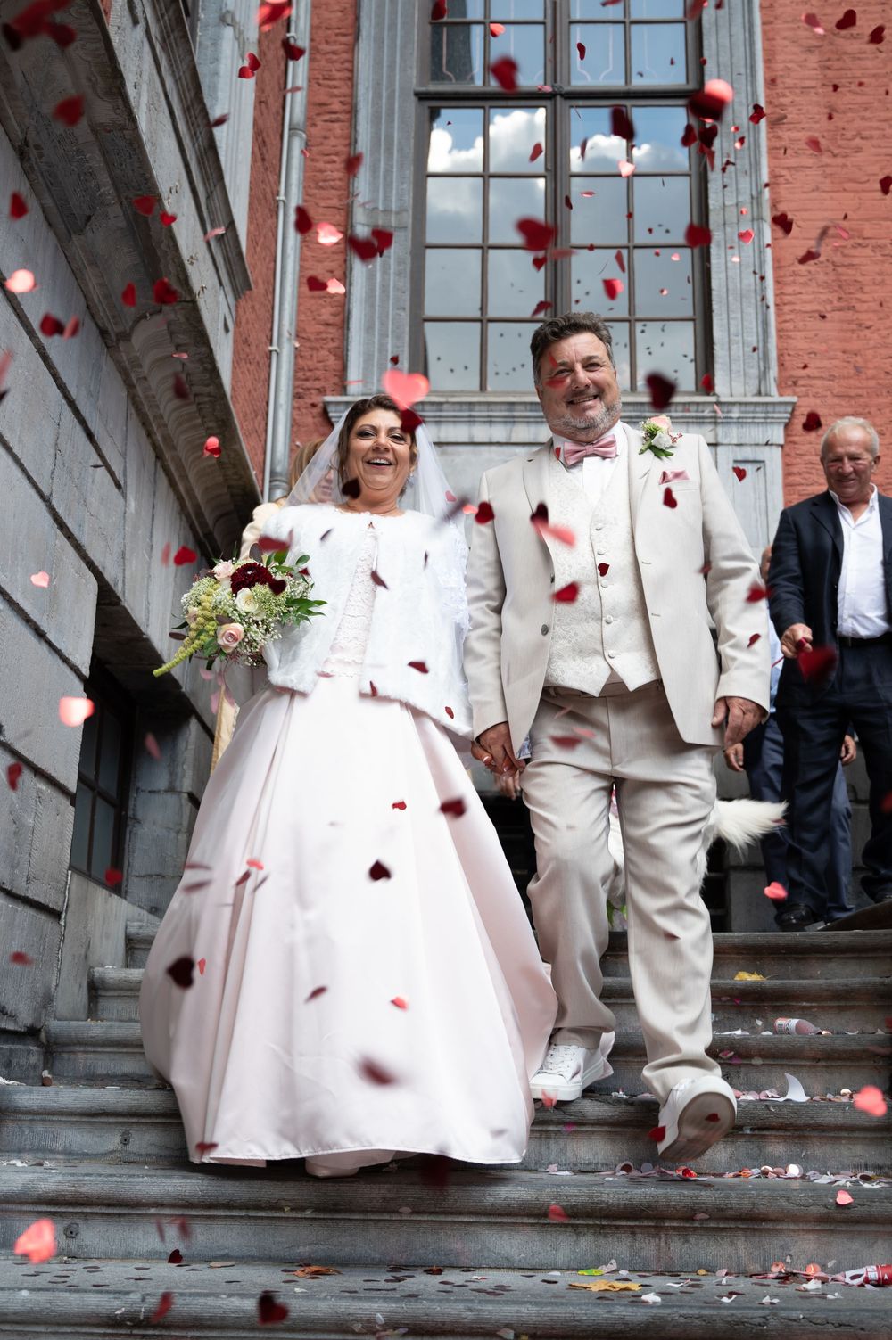À l’Hôtel de Ville de Liège, couple de mariés sortant de la cérémonie civile et descendant les escaliers sous des confettis en forme de cœur