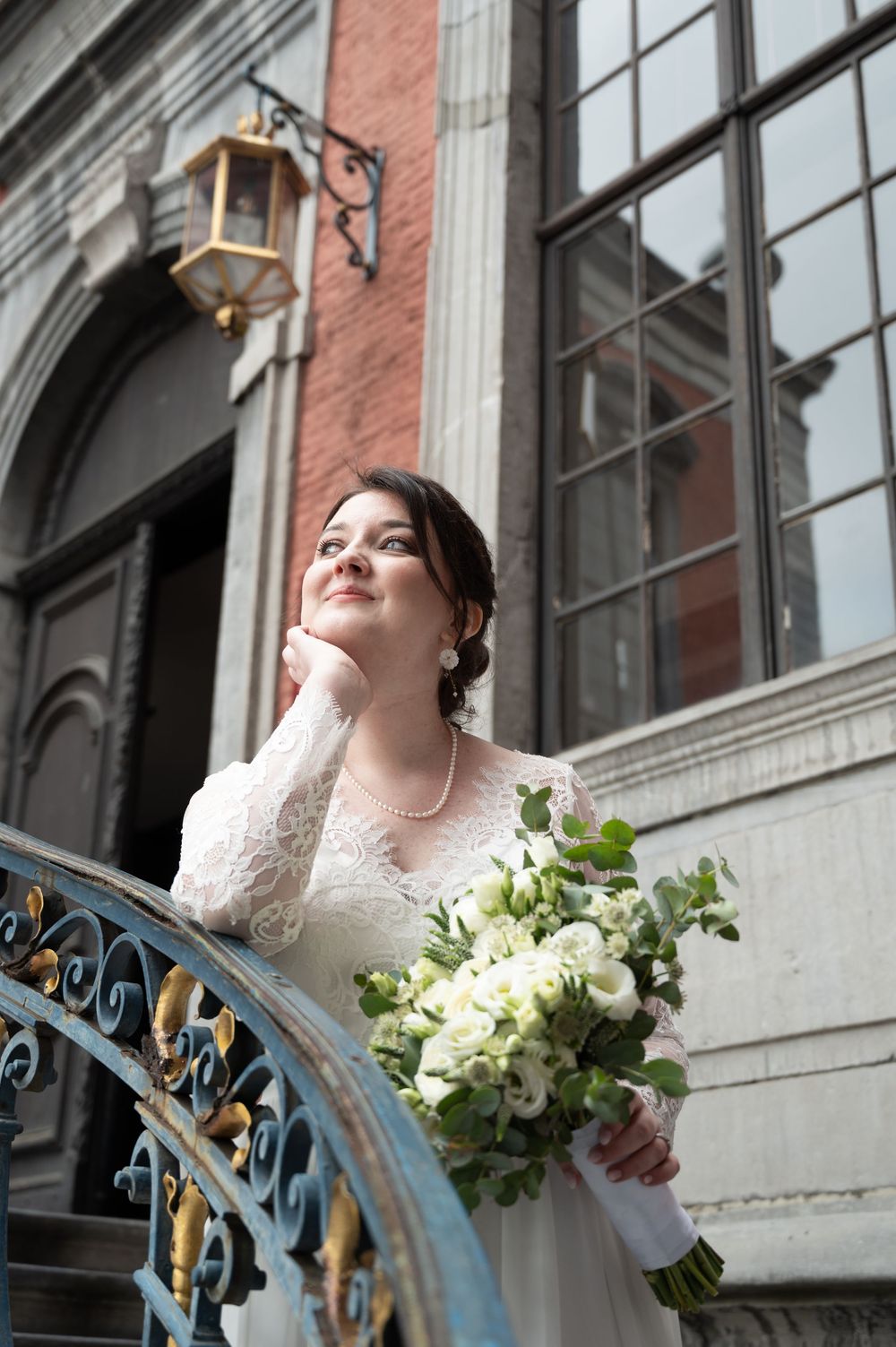 À l’Hôtel de Ville de Liège, mariée tenant son bouquet et attendant la cérémonie civile avec un regard tourné vers l’extérieur