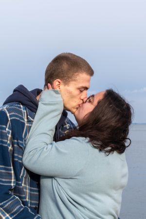 A romantic embrace between two people against a misty waterfront background.