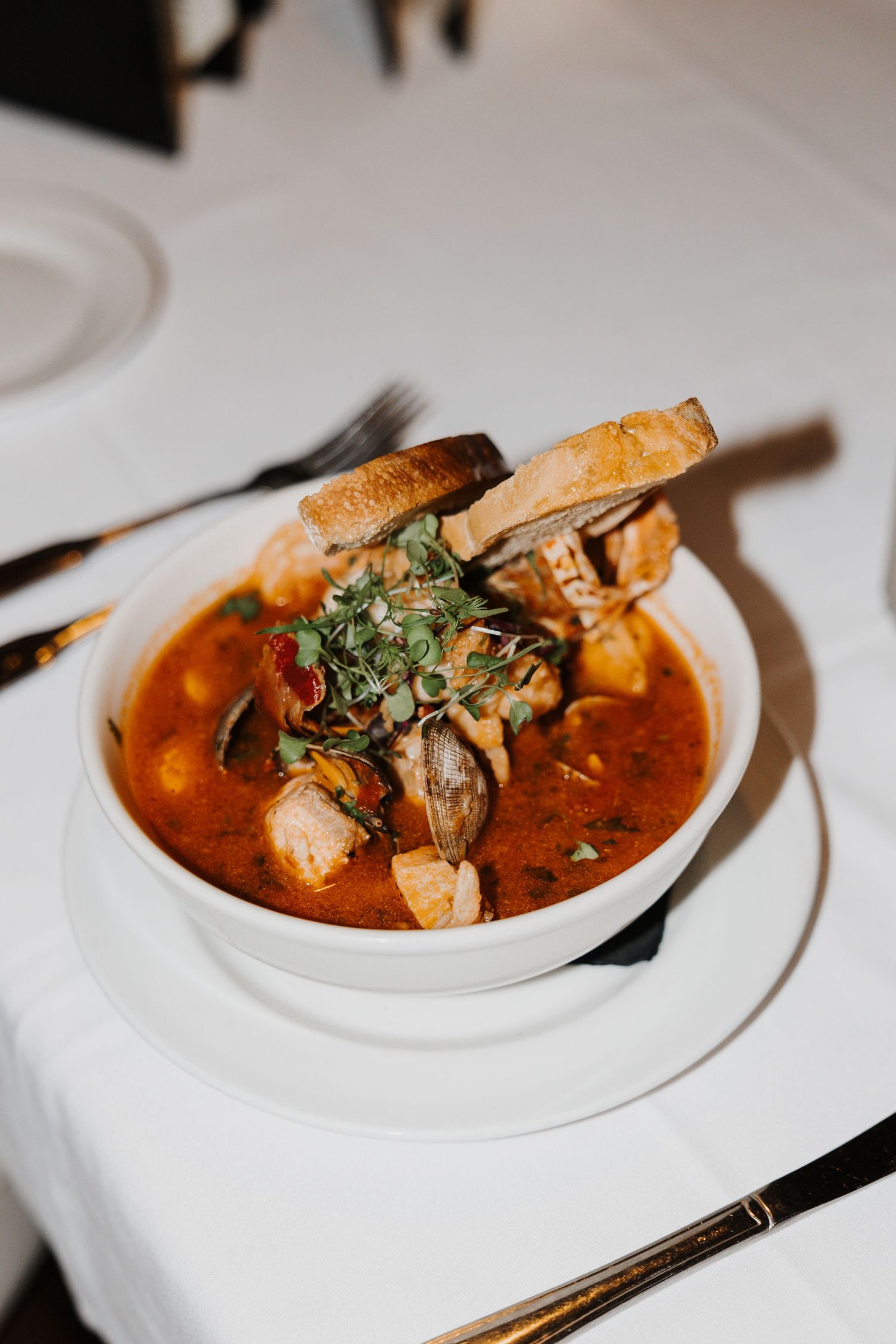Seafood stew with herbs served in a white bowl.