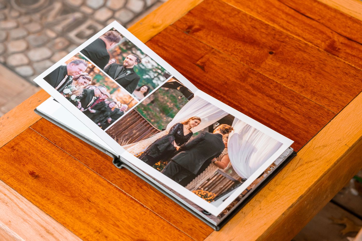 Wedding photo album open on wooden table showing multiple celebration photographs.