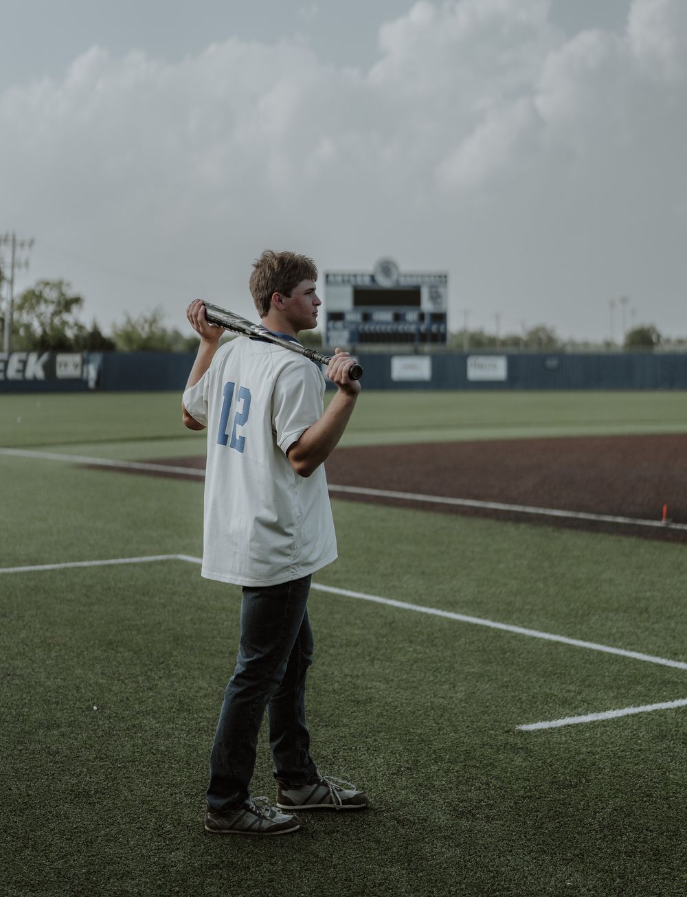 Young baseball player holding bat over shoulder on green field wearing jersey number 42.