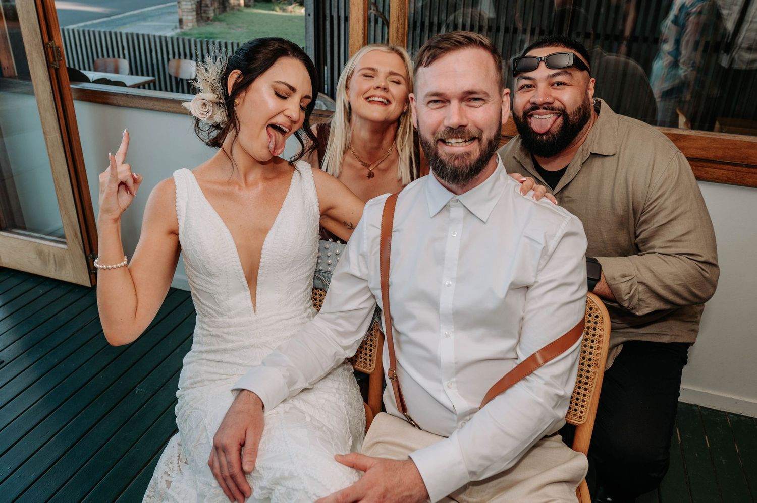 Wedding celebration group posing together on outdoor deck with casual joyful expressions.