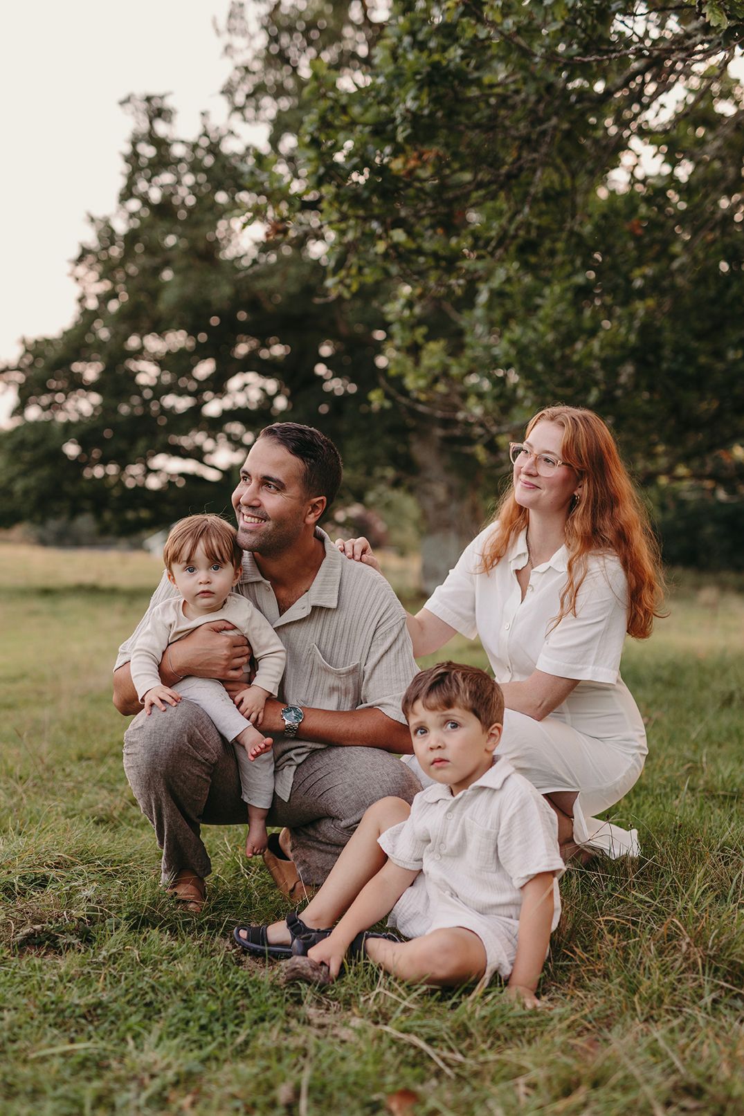 Pastoral summer scene with children running through a sunlit meadow near an old tree.