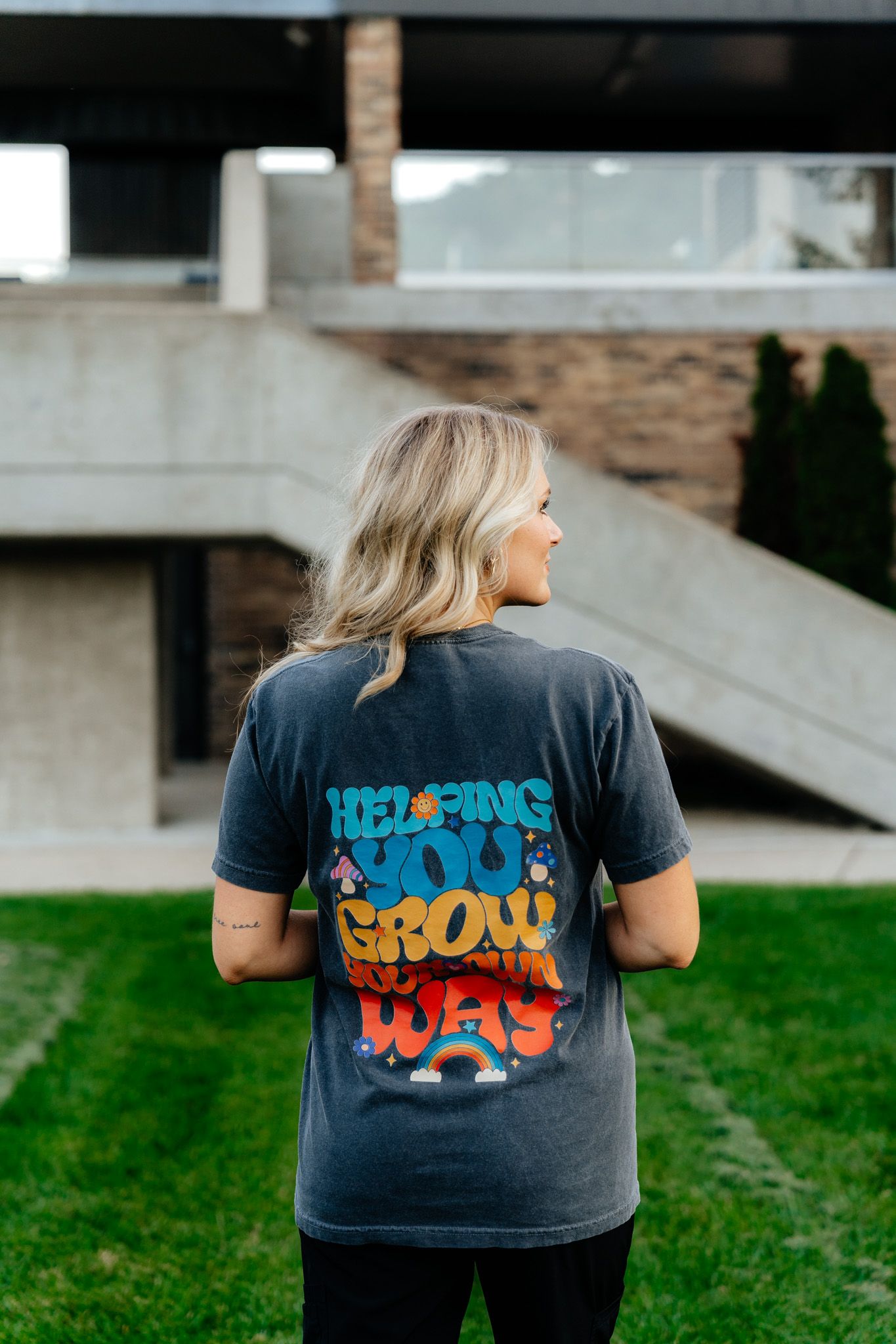 Back view of colorful graphic t-shirt with inspirational message on campus lawn.