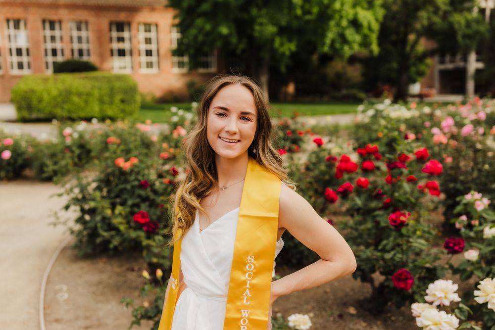 Graduation portrait in rose garden wearing yellow stole.