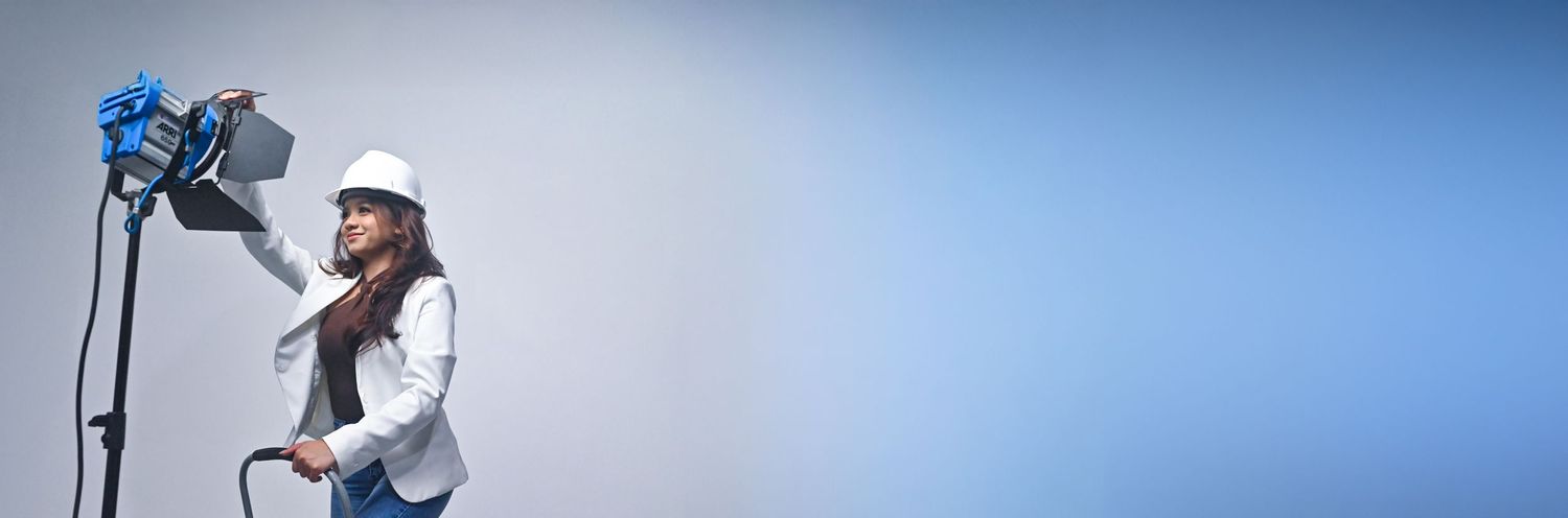 Camera operator adjusting equipment against a blue backdrop.