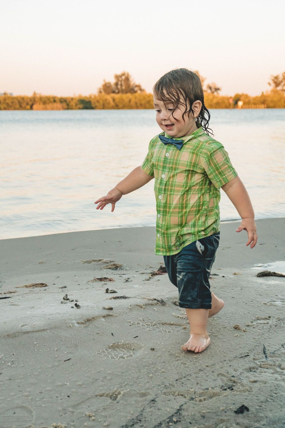 Young boy full of joy playing in the water during an outdoor family session in palm bay florida