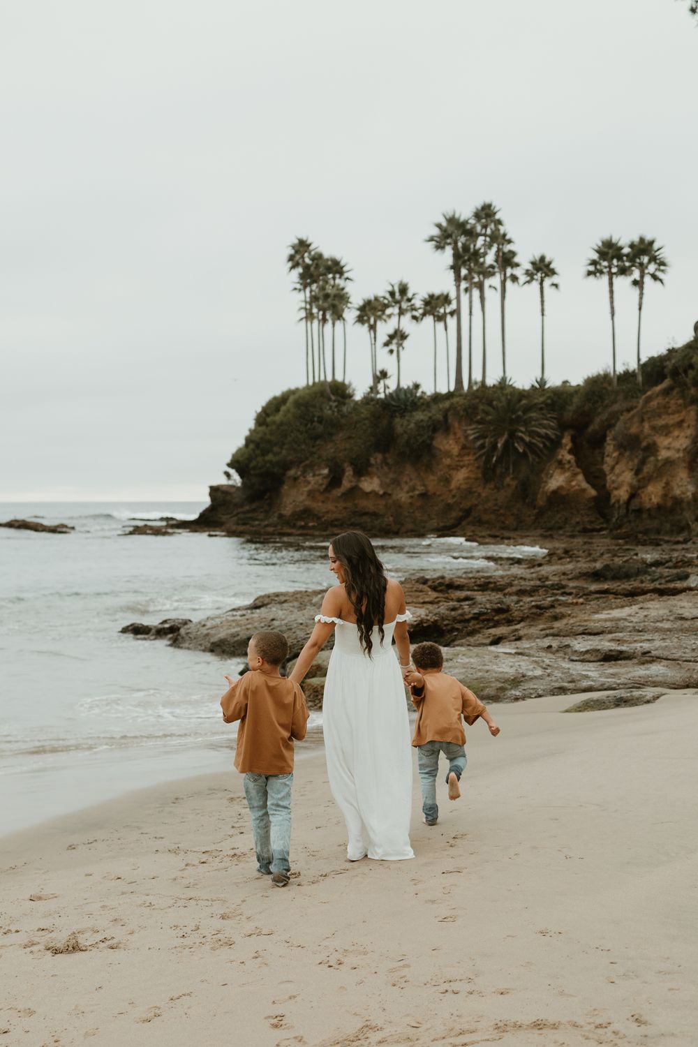 A beachside walk along the shore with palm trees towering on coastal cliffs.