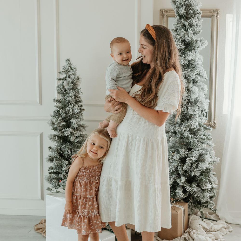 A heartwarming holiday scene with decorated Christmas trees and a white dress.