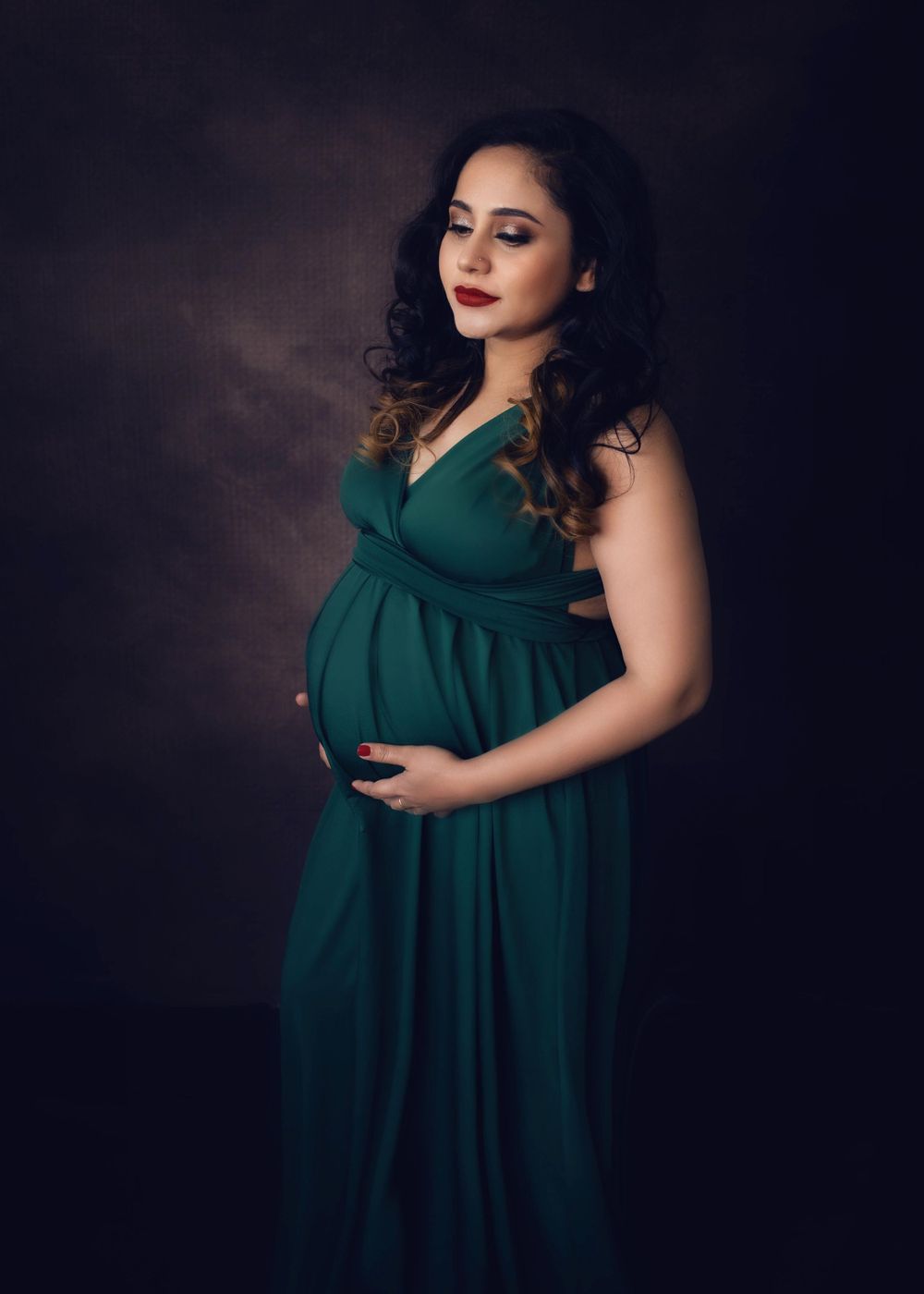 Maternity portrait of pregnant woman in forest green dress in painterly style.