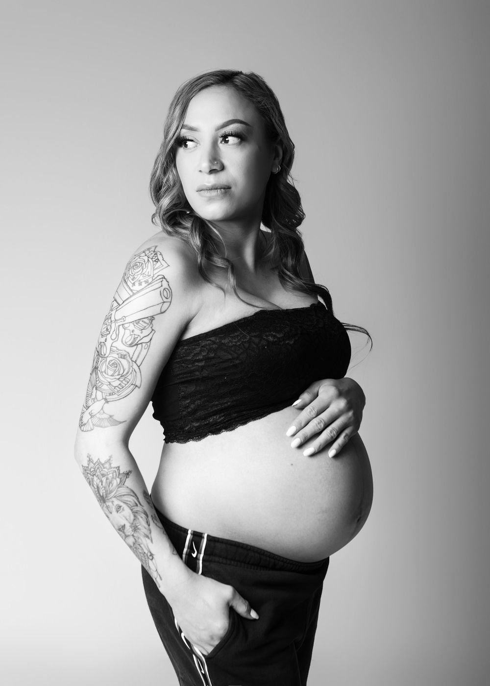 Black and white maternity portrait of Maori woman with tattoos on her harm.