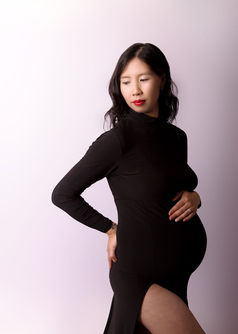 Maternity portrait of Chinese woman in black dress with a high slit and turtle neck.