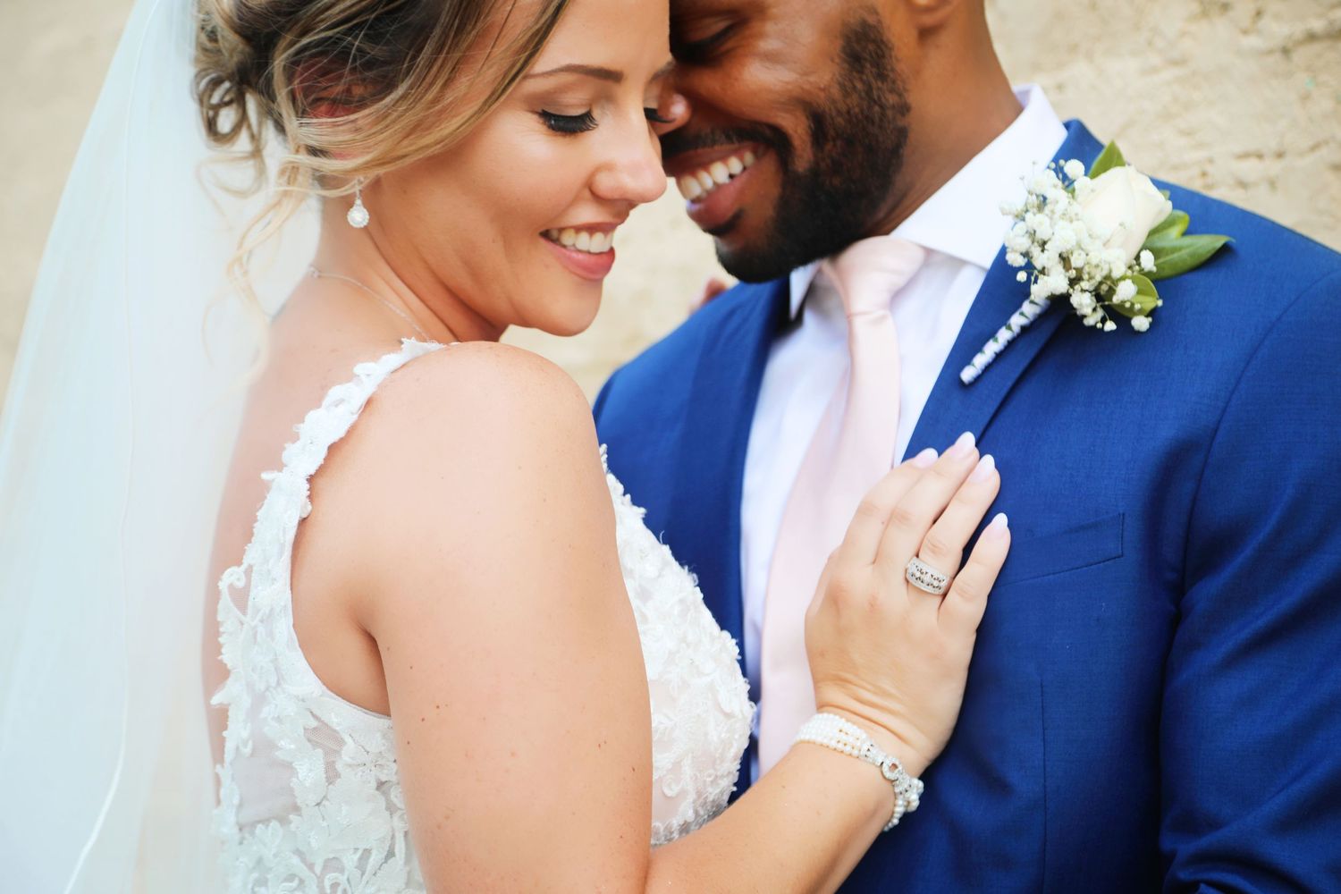 Intimate wedding couple moment with bride in lace dress and groom in blue suit.