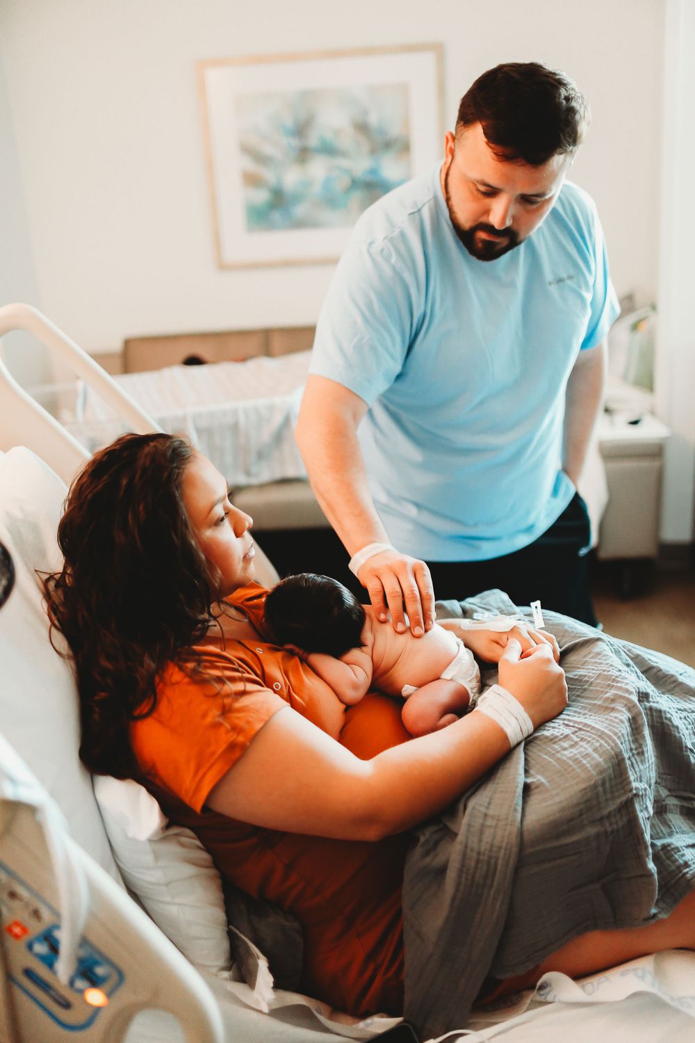 Dad staring a newborn baby son while mama holds him for fresh 48 session