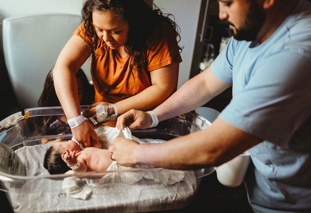 New mom and dad getting baby dressed for the first time for fresh 48 session